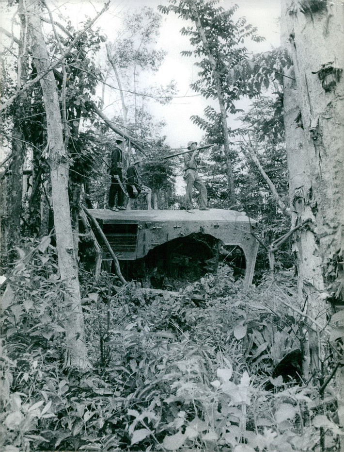 Các chiến sĩ du kích đứng trên xác một khí tài quân sự Mỹ trong rừng, 1967.
