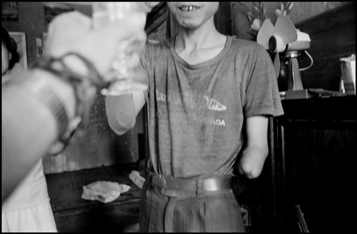 Người thương binh Việt Nam mời nhiếp ảnh gia nếm thử rượu gạo. Ảnh: Larry Towell - Magnumphotos.com