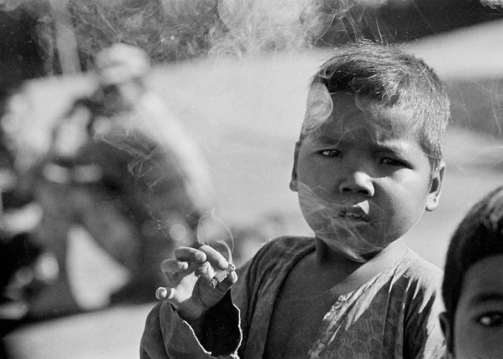 Một em bé hút thuốc lá xin từ lính Mỹ, tháng 3/1964. Ảnh: Horst Faas/ AP.