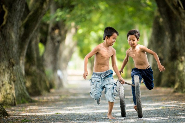 Hai cậu bé chơi đùa trên đường làng. Ảnh: Raymond Low - 500px.com
