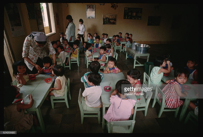 Một ni cô bón thức ăn cho trẻ em tại một lớp học tình thương ở Đà Nẵng, 2/8/1993. Hình ảnh nằm trong loạt ảnh Việt Nam năm 1993 của nhiếp ảnh gia người Mỹ Steve Raymer - phóng viên ảnh kỳ cựu của tạp chí National Geographic.