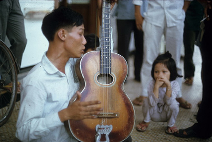 Người hành khất mù hát rong kiếm sống trên đường phố Sài Gòn.