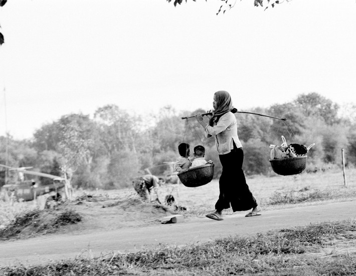 Một bà mẹ gánh những đứa con cùng hàng hóa trên vai ở làng Bến Súc, Củ Chi ngày 17/1/1967. Dân làng ở nơi đây bị buộc phải tản cư đến khu vực do quân đội Mỹ kiểm soát.