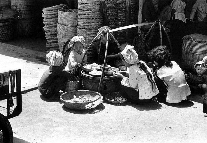 Các bé gái xúm xít quanh một gánh quà rong. Ảnh: Getty.