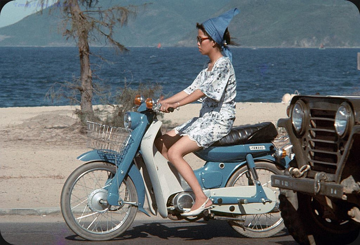 Vẫn là một chiếc xe Yamaha Dame màu xanh dương, nhưng lần này người cầm lái là một thiếu nữ tân thời.