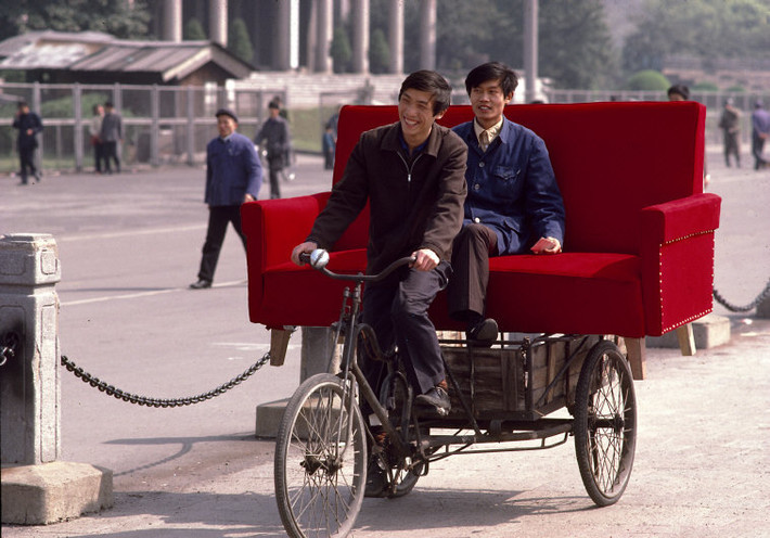 Người lái xe thồ chở chiếc ghế sofa đỏ trên đường phố. Ảnh: Thomas Hoepker/ Magnum Photos.