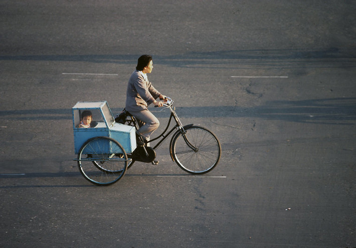 Người phụ nữ chở đứa con nhỏ trên chiếc xe đạp ba bánh tự chế. Ảnh: Thomas Hoepker/ Magnum Photos.