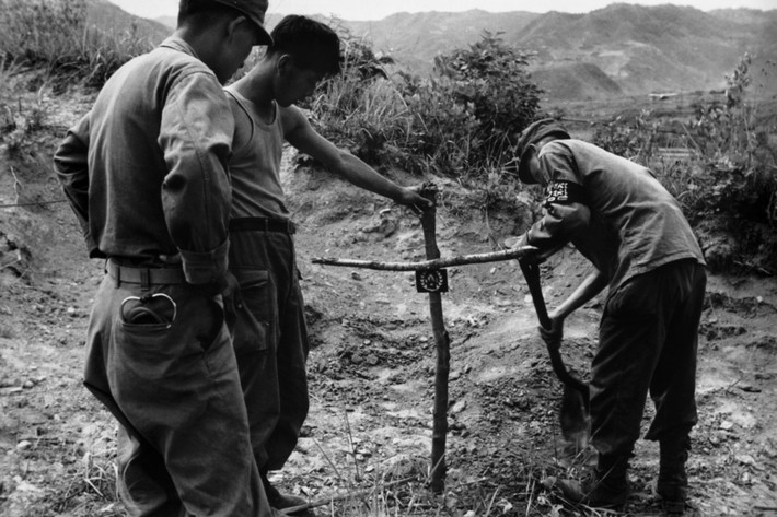 Lính Hàn Quốc chôn một người phụ nữ chết vì bệnh tật ở làng San Jang Ri. Trên thập tự bằng gỗ có gắn lá cờ Liên Hợp Quốc, tổ chức đứng đầu trên danh nghĩa của liên minh quân sự chống lại miền Bắc Triều Tiên. Ảnh: Werner Bischof.