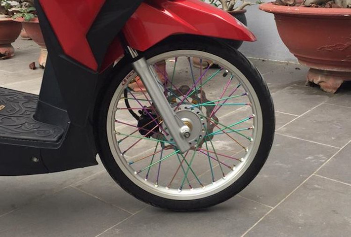 Ở dạng nguyên bản, Click 125i sử dụng vành đường kính 14 inch 5 cánh kép đẹp mắt nhưng trông khá "trống". Chính vì vậy, chủ xe đã thay hoàn toàn cặp vành đúc này bằng niềng nhôm 17 inch bản nhỏ, kèm theo bộ nan hoa 7 màu theo đúng phong cách kiểng Thái, khiến dáng của Click 125i trở nên nhẹ nhàng và cân đối hơn.