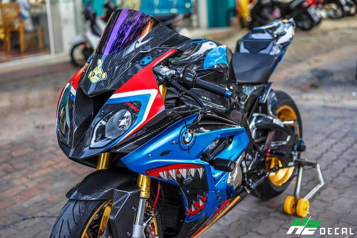 Trên nền dàn áo carbon, chủ xe đã dán trang trí chiếc S1000RR với hình ảnh của loài cá mập hai bên quây gió, tương xứng với biệt danh "cá mập" được nhiều biker Việt gọi chiếc xe. Trên khu vực tay lái là cùm côn và phanh Brembo RCS kèm tay Lightech, bình dầu Rizoma, bảo vệ tay phanh Lightech trong khi bên dưới là cặp chống đổ của R&G.