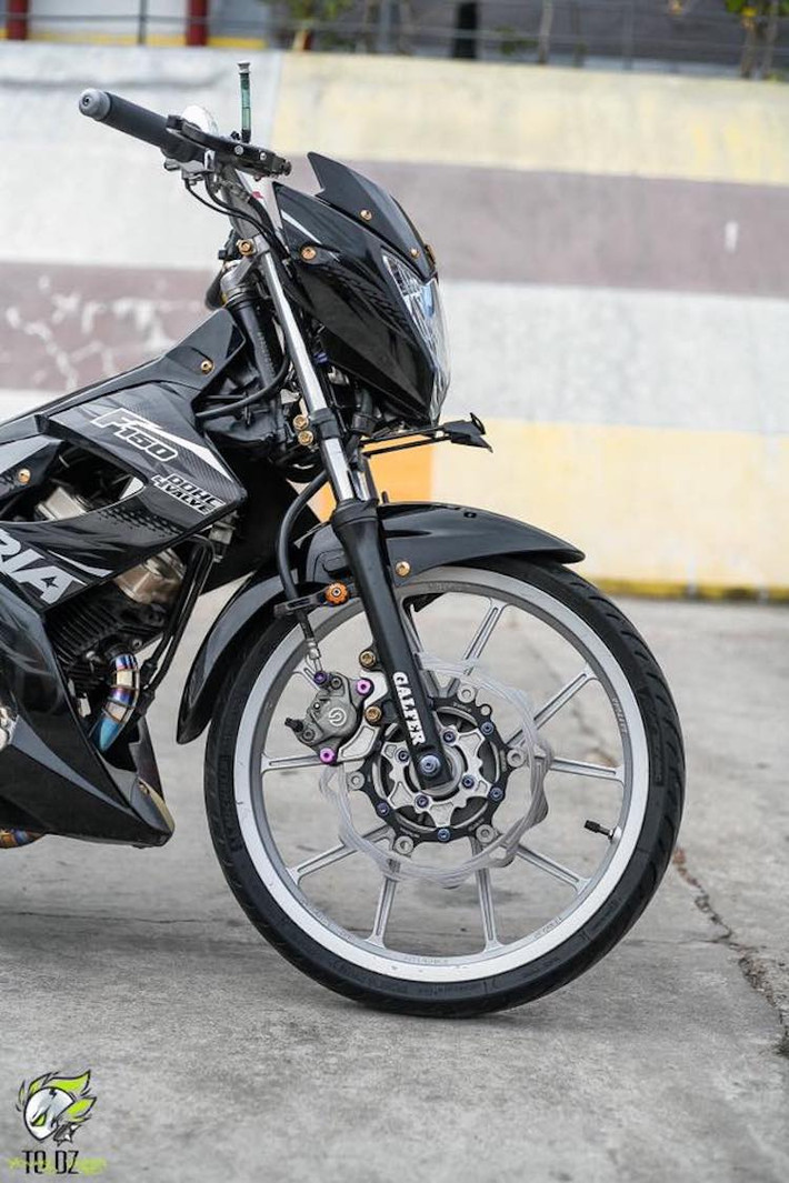 Thay vì cặp mâm 5 cây "xương cá" đặc trưng của Satria F150 hay Raider, chủ xe đã thay bằng mâm Daytona 5 cây chữ Y "hàng hiệu". Để khiến chiếc xe nhẹ nhàng hơn, bộ lốp Michelin Pilot Street bản mỏng đã được sử dụng. Hệ thống phanh trước được nâng cấp tổng thể với heo Brembo 2 pis đối xứng, đĩa hoa Galfer lòng CNC và cùm phanh Brembo.