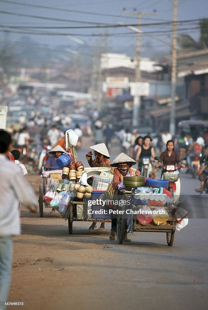 Những người phụ nữ đẩy xe bán hàng gia dụng trên đường phố.