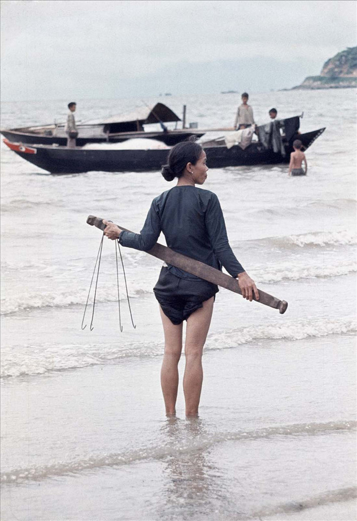 Người phụ nữ chờ đợi thuyền cá về bến.