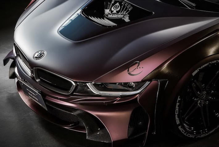 Với gói độ EVO, toàn bộ phần cản trước của i8 đã được hãng Energy Motor Sport thay mới hoàn toàn, với những cánh khí động học độc đáo và phần lưới hút gió rộng hơn nhiều so với xe zin. Nằm phía trên nắp ca-pô của xe là hình ảnh những lá "át chủ bài" gắn với nhân vật Joker.