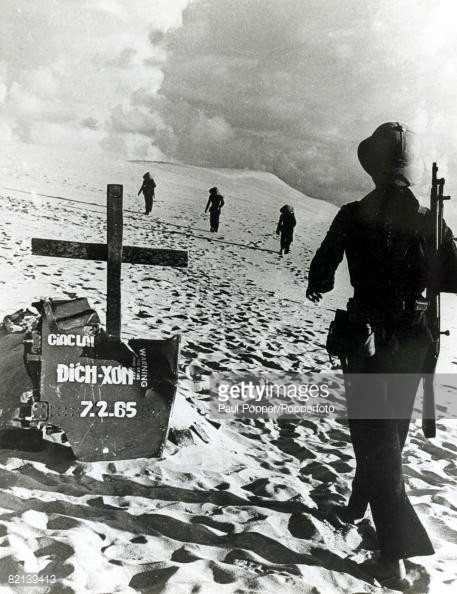 Quảng Bình năm 1970, một nhóm nữ dân quân bước qua "nấm mộ" làm bằng mảnh xác máy bay của một "giặc lái" Mỹ tên Dickson bị bắn rơi tại đây ngày 7/2/1965. Ảnh: Paul Popper/Popperfoto - GettyImages.