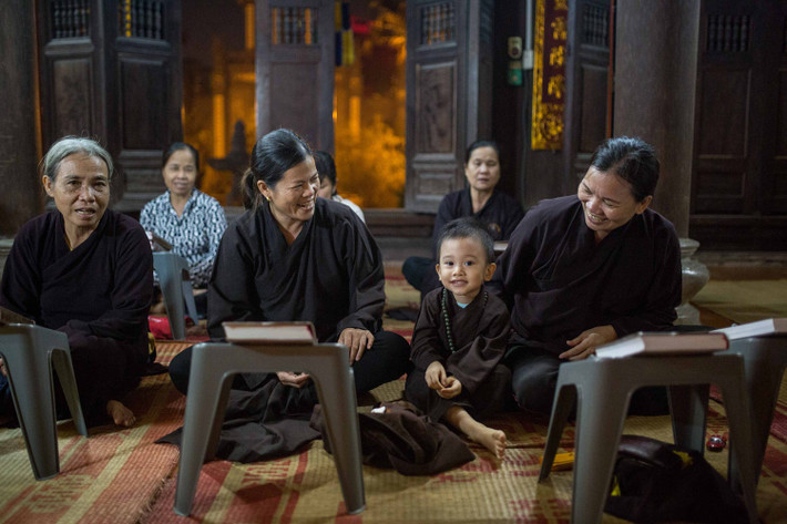 Em bé đi tụng kinh trên chùa cùng bà ở Hà Nội. Ảnh: Mathieu Arnaudet - 500px.com.