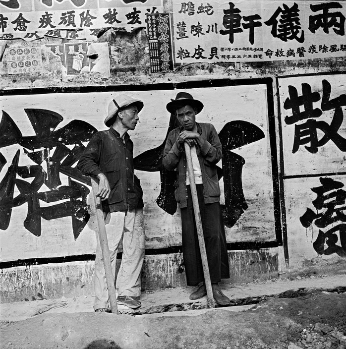 Hai người cửu vạn cầm cuốc trước một hố lớn đang đào dở. Ảnh: Werner Bischof / Magnum Photos.