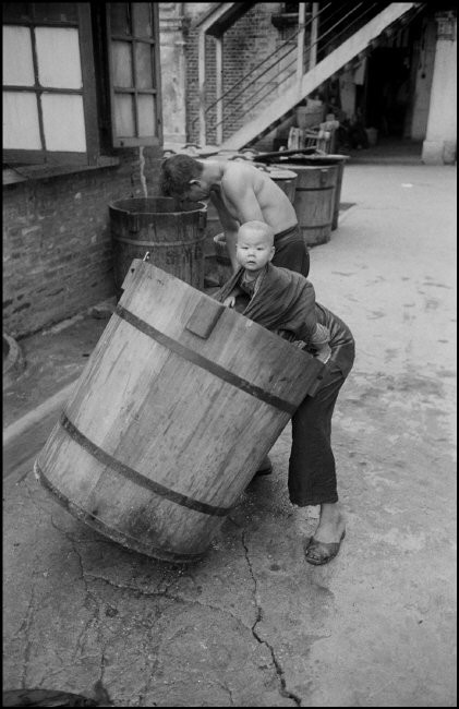 Một người phụ nữ lao động khi vẫn địu con trên lưng. Ảnh: Werner Bischof / Magnum Photos.