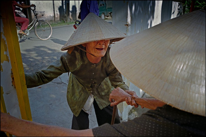 Hai cụ bà chào hỏi nhau trên đường phố ở Phong Điền. Ảnh: Ian Berry/ Magnum Photos.