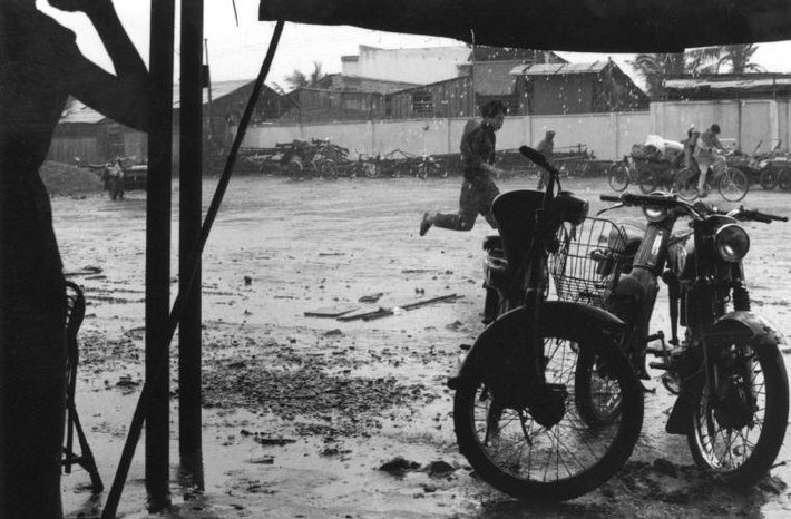 Cơn mưa bất chợt khiến người đi đường nháo nhác, Sài Gòn năm 1993. Ảnh: Ferdinando Scianna/ Magnumphotos.com.