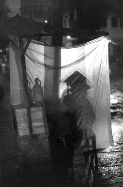 Một quầy hàng vỉa hè trong đêm mưa Sài Gòn. Ảnh: Ferdinando Scianna/ Magnumphotos.com.