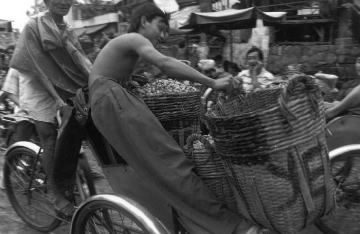 Cậu bé giữ các giỏ hàng trên một chiếc xích lô, Sài Gòn năm 1993. Ảnh: Ferdinando Scianna/ Magnumphotos.com.
