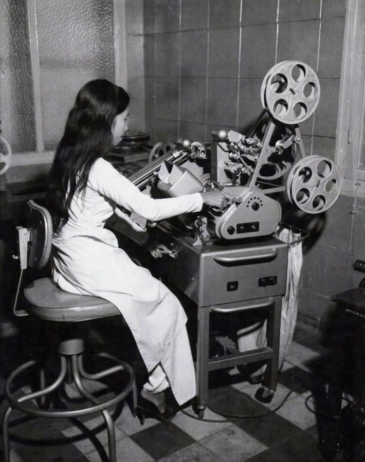 Một kỹ thuật viên nữ đang kiểm tra các đoạn phim 35mm Sound Moviola ở phòng chế bản của đài truyền hình Sài Gòn trước khi chuyển đổi về định dạng phim 16mm và tiến hành lồng âm, ngày 23/1/1967.