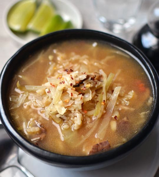 Trong lúc chờ đợi canh gạo chín thì dùng tay xé nhỏ thịt gà ra. Khi hạt gạo đã mềm, cho thịt gà xé vào nồi cùng với bắp cải, nước chanh và nước tương, nấu thêm khoảng vài phút nữa hoặc cho đến khi bắp cải nóng và mềm là được.