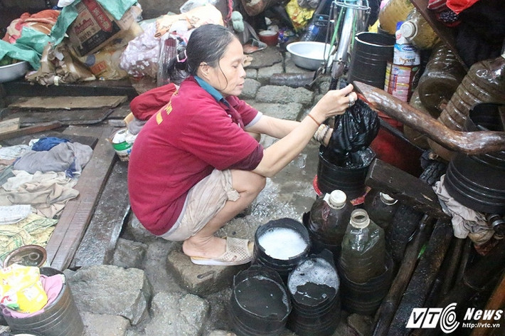 Chị Minh đang giật quần áo trong những chiếc chậu tự chế.