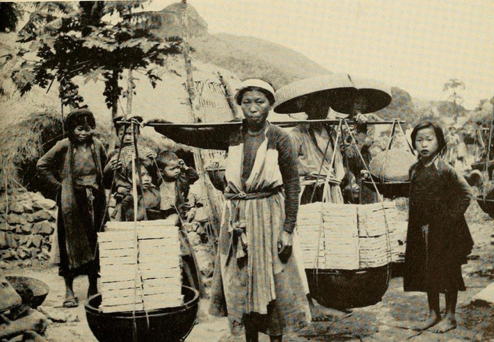 Một phụ nữ gánh vàng mã ra chợ ở làng Đông Sơn, Thanh Hóa. Ảnh: The People of French Indochina.