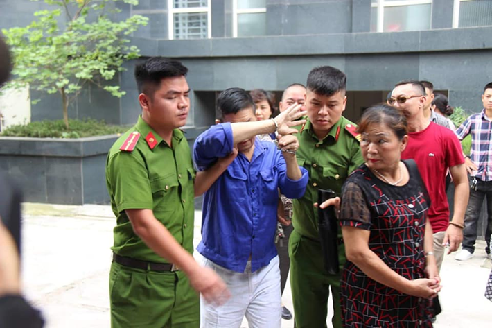 Trùm bảo kê chợ Long Biên - Hưng "kính" được 2 cảnh sát áp giải.