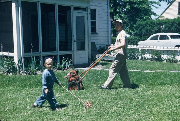 Em bé phụ bố cắt cỏ trước sân nhà ở bang Ohio, 1951. Ảnh: Walter Reed.