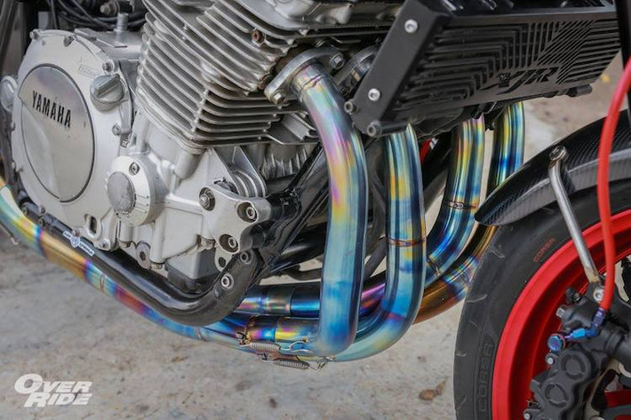 Trên bản độ này, chủ xe đã cập nhật nhẹ động cơ bằng cách độ lọc gió K&N, tinh chỉnh chế hòa khí và độ hệ thống xả titan. Cây pô Termignoni carbon lấy từ xe Ducati không chỉ khiến XJR1300 "thoáng máy" hơn mà còn khiến tiếng "hú" đặc trưng của động cơ 4 xi-lanh trở nên to và rõ ràng hơn.