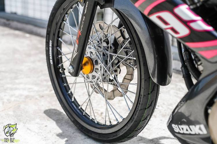 Dòng xe côn tay Satria 150 hay Raider 150 vốn nổi tiếng bởi thiết kế mâm đúc 5 cây "xương cá" độc đáo. Tuy nhiên trên bản độ này, chủ xe đã thay cặp mâm nguyên bản bằng bánh căm với niềng nhôm Racing Boy. Hệ thống phanh trước của chiếc xe cũng được độ lại bằng heo Brembo 2 pis đối xứng và đĩa Galfer.