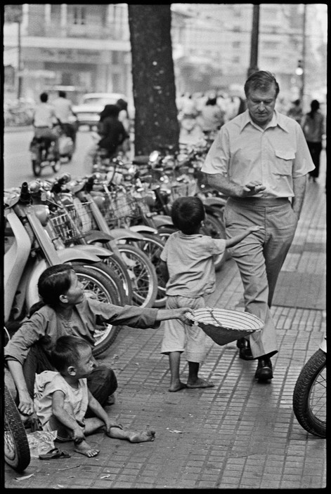 Ba mẹ con ăn xin người nước ngoài trên vỉa hè đại lộ Lê Lợi. Ảnh: Magnumphotos.com.