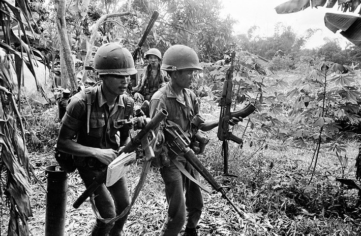 Lình Sài Gòn cầm một khẩu AK-47, lựu đạn và bản đồ thu được từ quân đội Giải phóng sau khi tái chiếm ngôi làng gần Quốc lộ 13. Ảnh: Magnumphotos.com