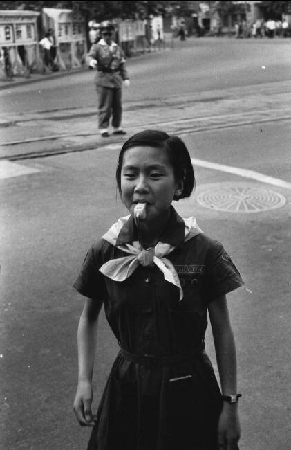 Nữ sinh giúp cảnh sát giao thông chỉ dẫn các học sinh qua đường. Ảnh: Rene Burri/ Magnum Photos.