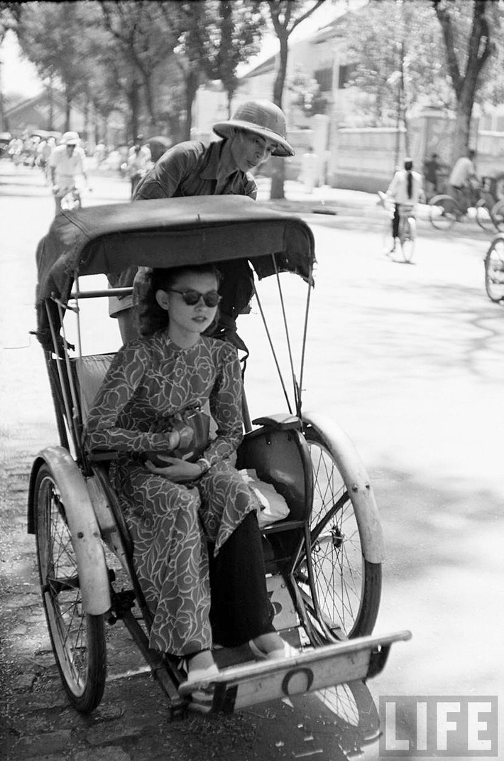 Một phụ nữ mặc áo dài ngồi trên xe xích lô ở Sài Gòn năm 1950. Ảnh: Carl Mydans/ Life.