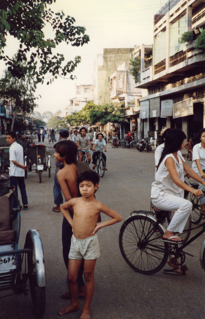 Chú bé đứng chống nạnh trên con phố đông.