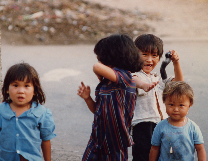 Một nhóm trẻ em trên đường phố. Chú bé phía sau cầm cuộn phim trên tay.