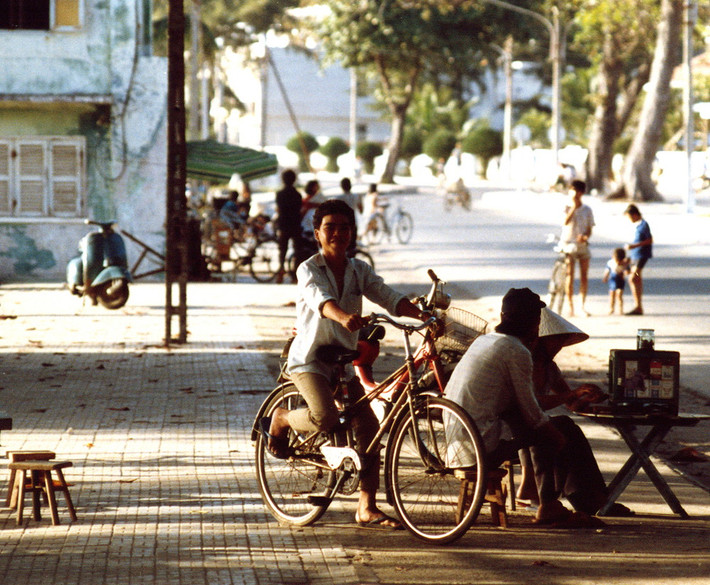Thanh niên ngồi trên yêu sau xe đạp cười tươi khi được chụp hình.