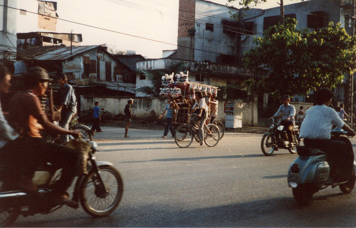 Một chiếc xích lô chở đầu lân chạy trên đường.