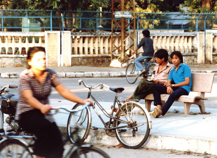Hai thiếu niên ngồi trên ghế đá ngắm đường phố.