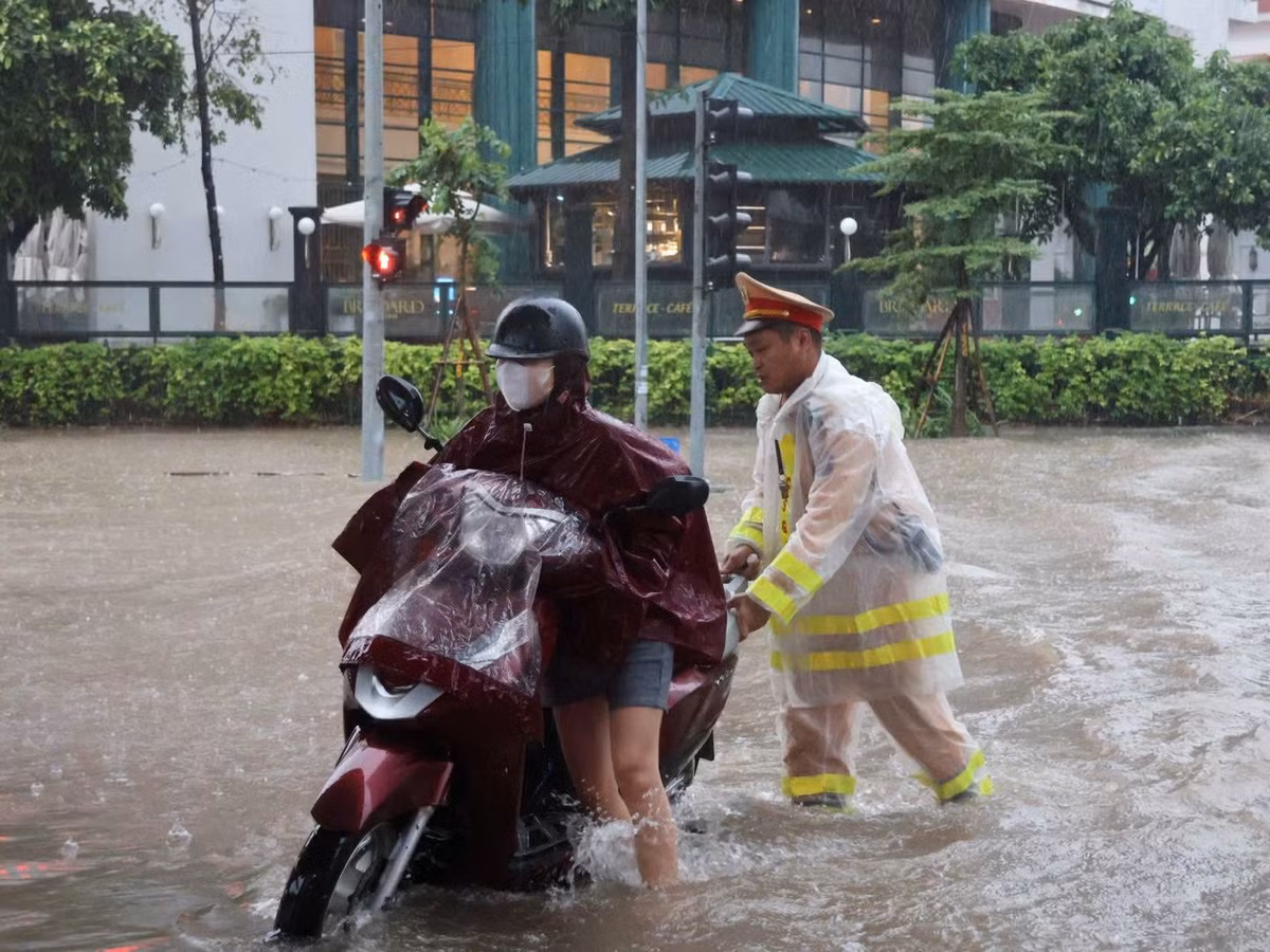 Đường phố Hà Nội ngập sâu kéo dài, ngoài việc bảo đảm phân luồng giao thông, cán bộ CSGT còn luôn dầm mưa để hỗ trợ việc di chuyển cho người dân qua các đoạn ngập lụt.