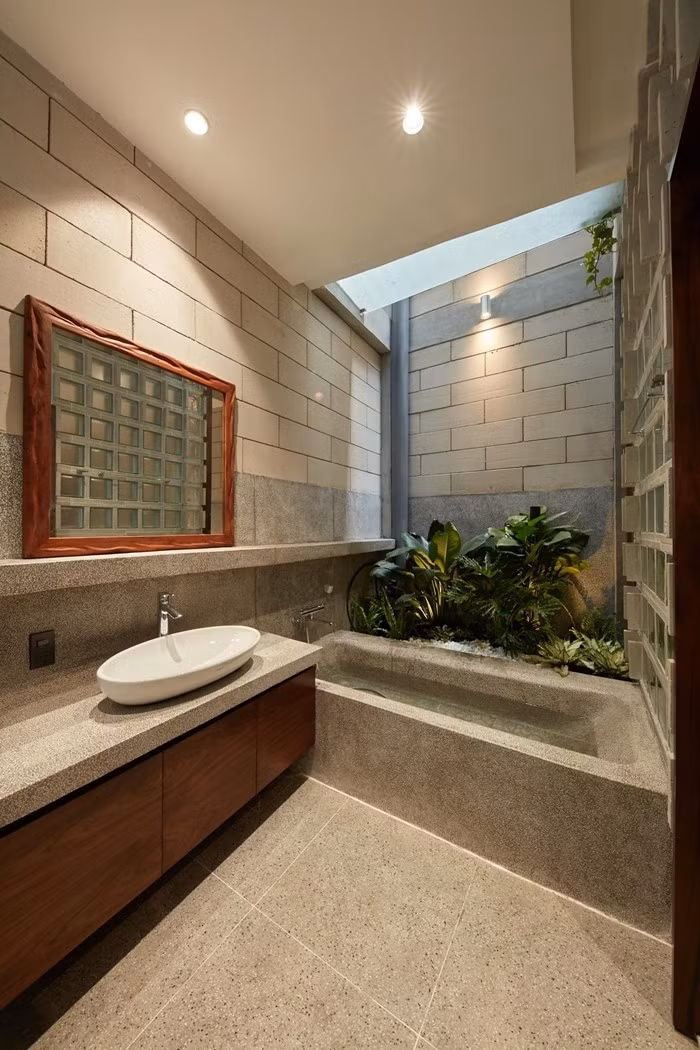 Khu vệ sinh nối liền phòng ngủ, có bồn tắm bê tông đón ánh sáng tự nhiên từ giếng trời giúp tận dụng tối đa ánh sáng tự nhiên và thông gió. Ảnh: Thiết Vũ