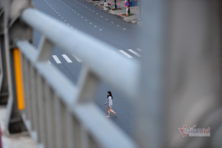 Một cô gái vội vã băng qua đường tại ngã tư Hàng Xanh sau giờ cấm ra đường