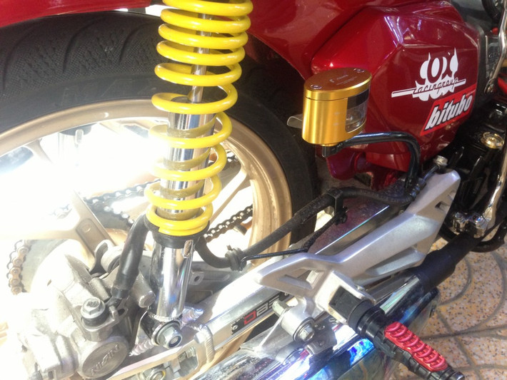 Đồ chơi đằng sau xe gồm: phuộc Nice quen thuộc, gác chân biker, gắp nhôm DBS, bình dầu Rizoma vàng.
