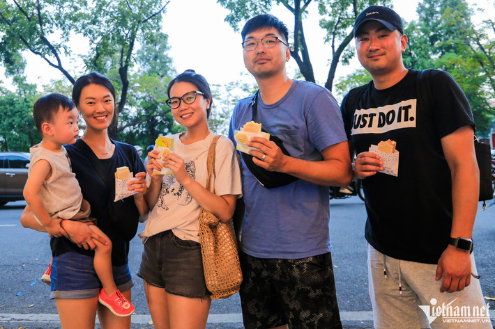 Chị Ánh và anh Sung (giữa, về Hà Nội từ Mỹ) sau một hồi loay hoay nhìn hai hàng kem kẹp Singapore gần nhau đã không biết chọn quán nào. Cuối cùng chị Ánh quyết định mua mỗi bên 2 chiếc. "Tôi thấy kem ở hai cửa hàng hương vị đều giống nhau, đều có mùi thơm của trái cây và không bị quá ngọt", người phụ nữ chia sẻ.