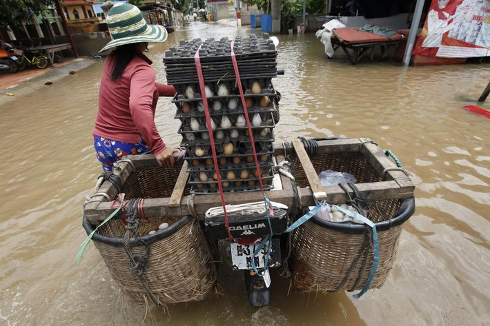 Một phụ nữ đẩy xe máy chở trứng đi bán.