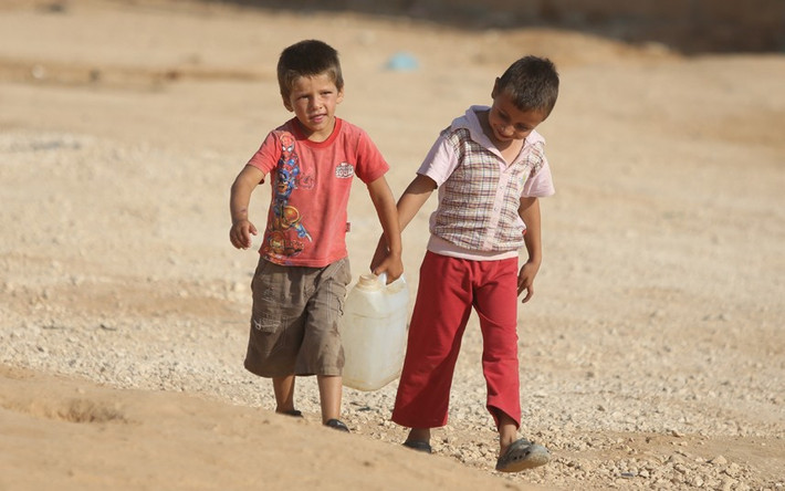 Hai cậu bé người Syria xách nước về lều của gia đình mình.